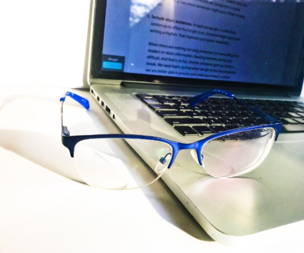 Metallic blue glasses resting on an open laptop
